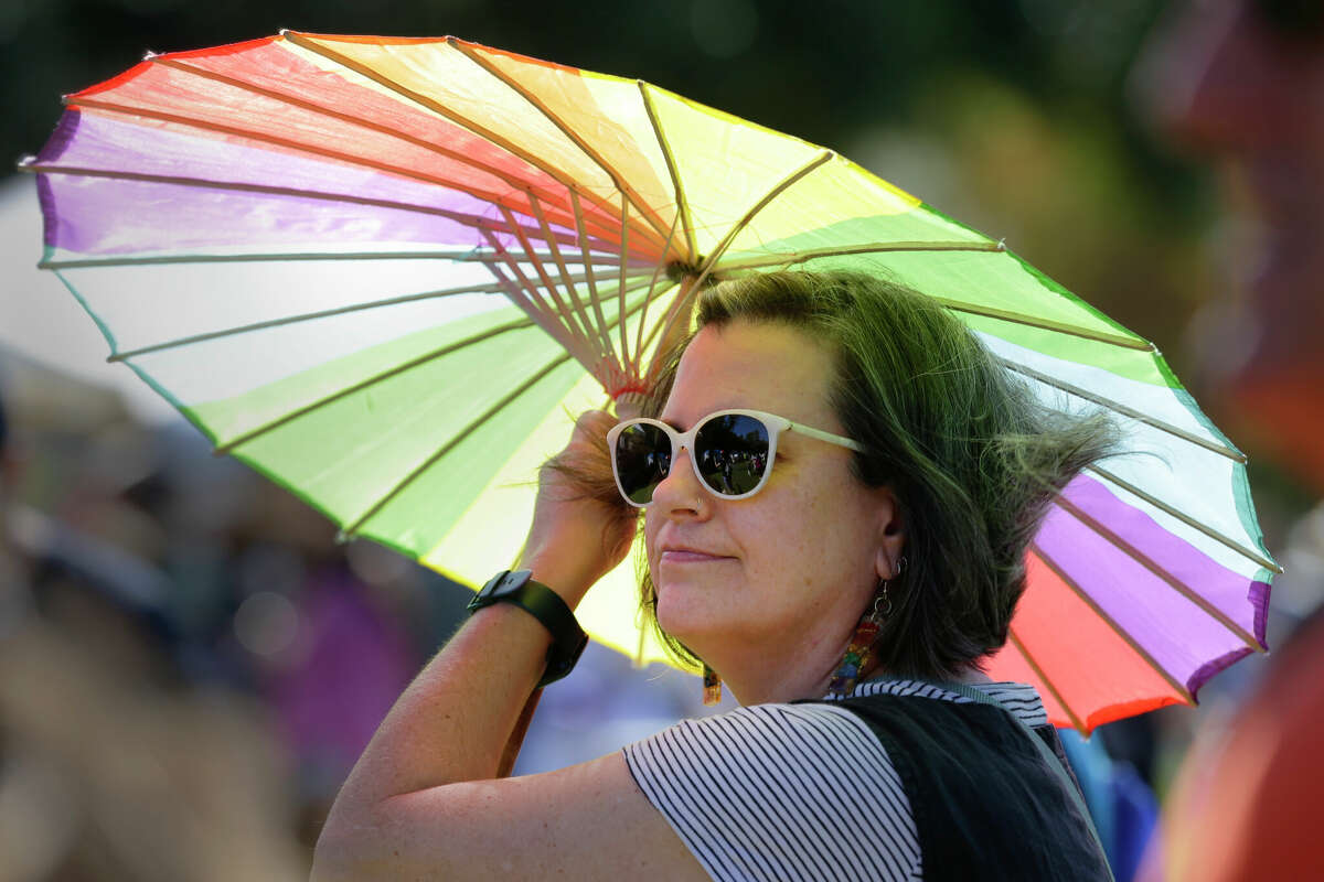 Erika Richie stands under a pride umbrella as she listens to music played by the Houston Pride Band during the 4th annual Woodlands Pride Festival held at Town Green Park Saturday, Oct. 22, 2022 in The Woodlands, TX.