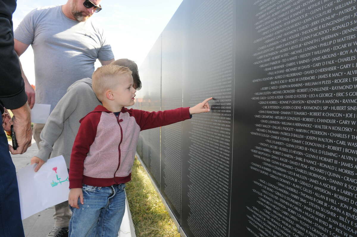 Three-year-old Jarrett Moorman of Edwardsville examines the names on the American Veterans Traveling Tribute Memorial Wall. The memorial was in Troy Thursday through Sunday.