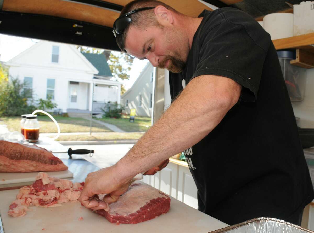 Brandon Crews of Troy prepares brisket to be barbecued for the Tongue Punch Barbecue team in Edwardsville on Saturday at the inaugural Que & Brew Festival.
