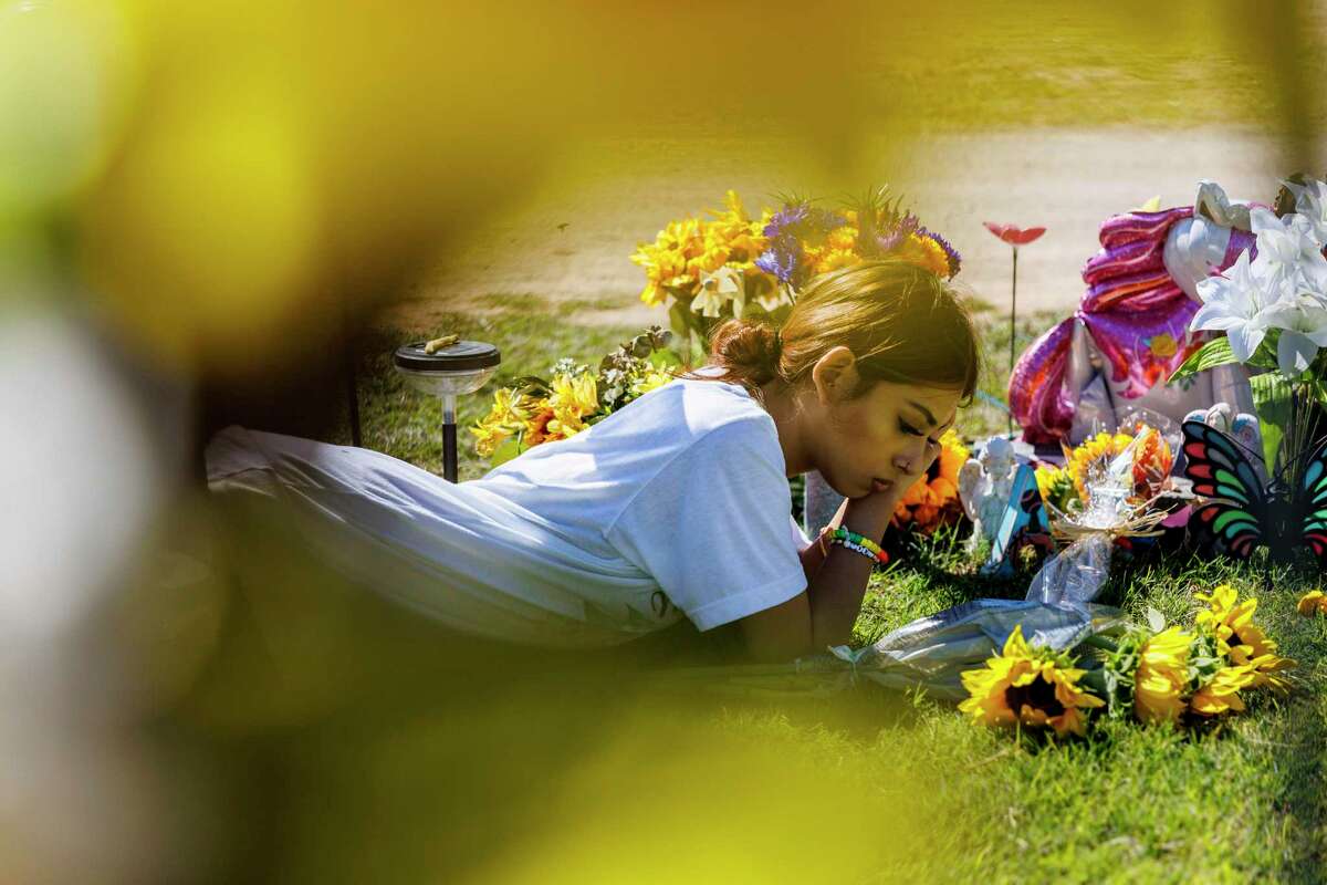 Kalisa Barboza, 18, lies beside her sister Lexi Rubio’s grave in Hillcrest Memorial Cemetery in Uvalde, Texas, Thursday, Oct. 20, 2022. Lexi, one of 19 school children and two teachers killed at Robb Elementary on May 24, would have turned 11 on Thursday.