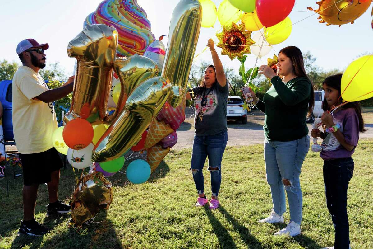 Felix Rubio helps family tie up more balloons to decorate his daughter Lexi Rubio’s grave at Hillcrest Memorial Cemetery in Uvalde Thursday. Lexi would have turned 11 on Thursday. Her family spent the day decorating her grave with balloons and flowers as they shared food and listened to music to celebrate her life.