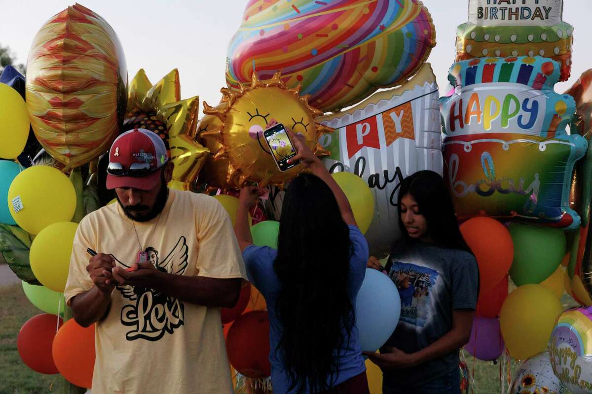 Felix Rubio, from left, writes a personalized note to his daughter Lexi Rubio as his wife Kimberly Mata-Rubio takes a picture of their 9-year-old son Julian’s note while their daughter Jahleela Rubio, 11, picks a balloon to release at Lexi’s grave in Hillcrest Memorial Cemetery in Uvalde. Lexi would have turned 11 on Thursday.