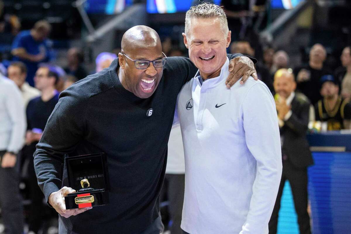 Kings coach Mike Brown, left, is presented his NBA championship ring by Warriors coach Steve Kerr.
