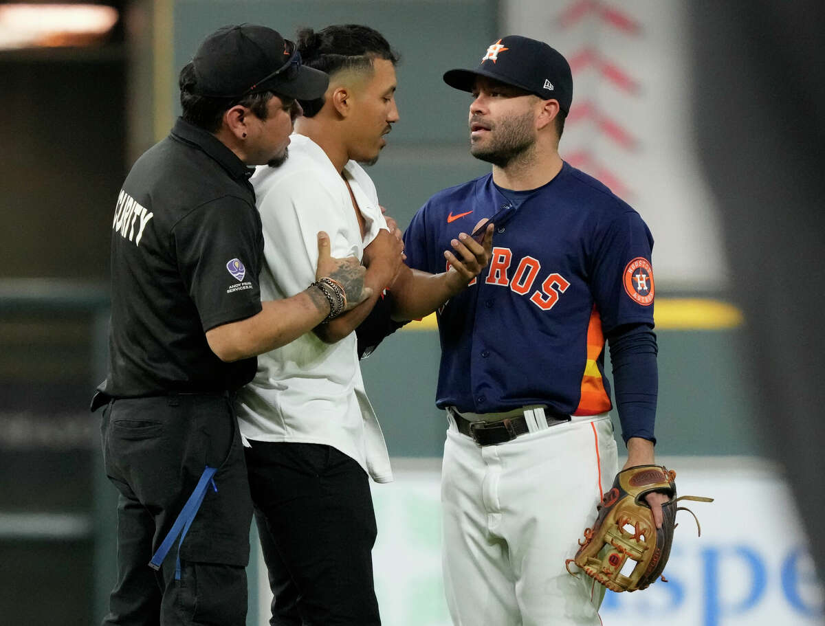 Houston Astros second baseman Jose Altuve (27) talks with a fan who ran onto the field as he is taken away by security during the eighth inning in Game 2 of the American League Championship Series at Minute Maid Park on Thursday, Oct. 20, 2022, in Houston.