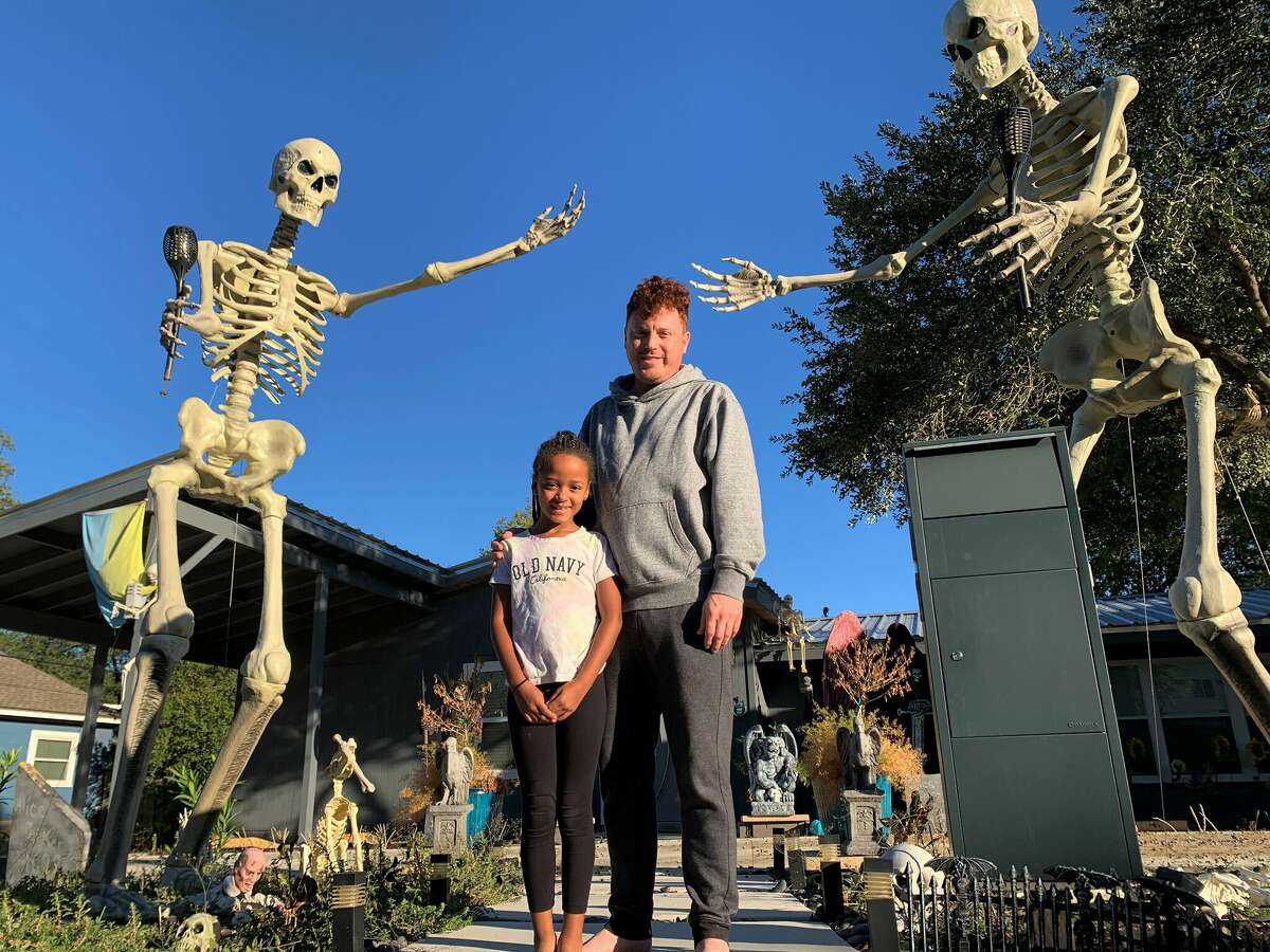 Kevin Stanton and his 8-year-old daughter, Chloe, stand outside their San Antonio home guarded by two 12-foot Home Depot skeletons. The Halloween yard props have become best sellers and are hard to come by. 