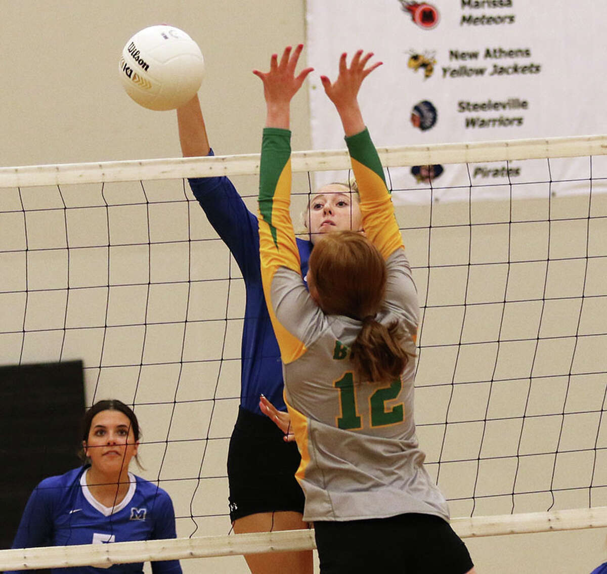 Marquette's Kylie Murray attacks against the block by Southwestern's Abigail Hellrung (12) in a semifinal match Monday night at the Wesclin Class 2A Regional at Trenton.