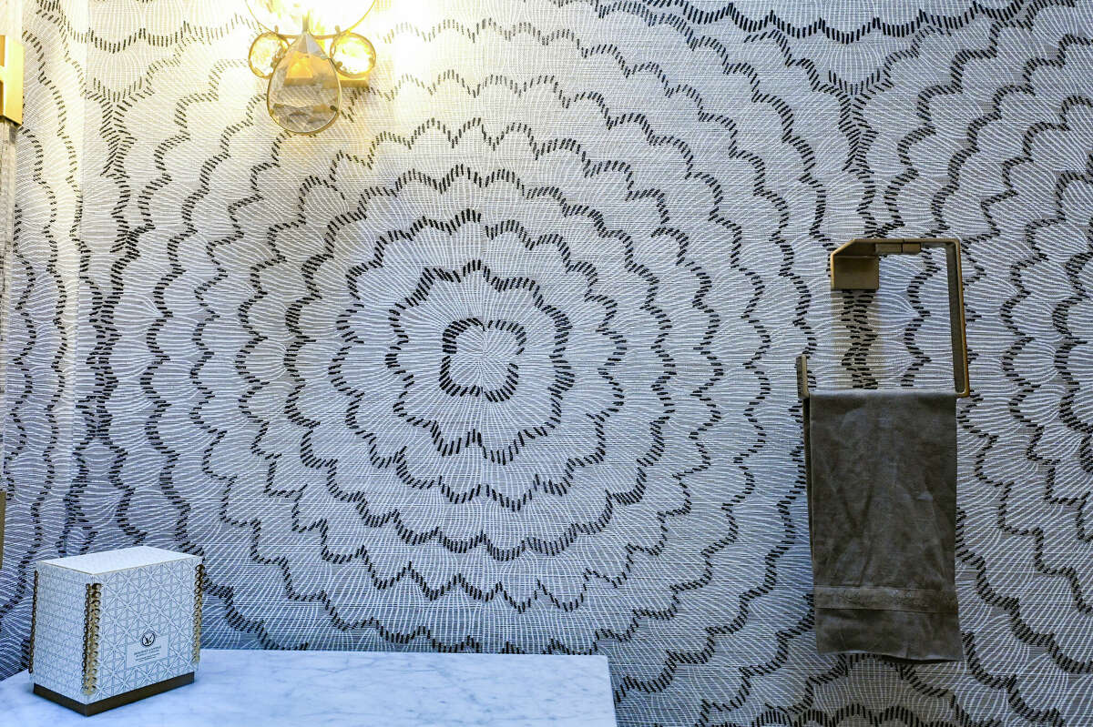 The powder room dazzles with textured wallpaper of large, wavy concentric circles. 