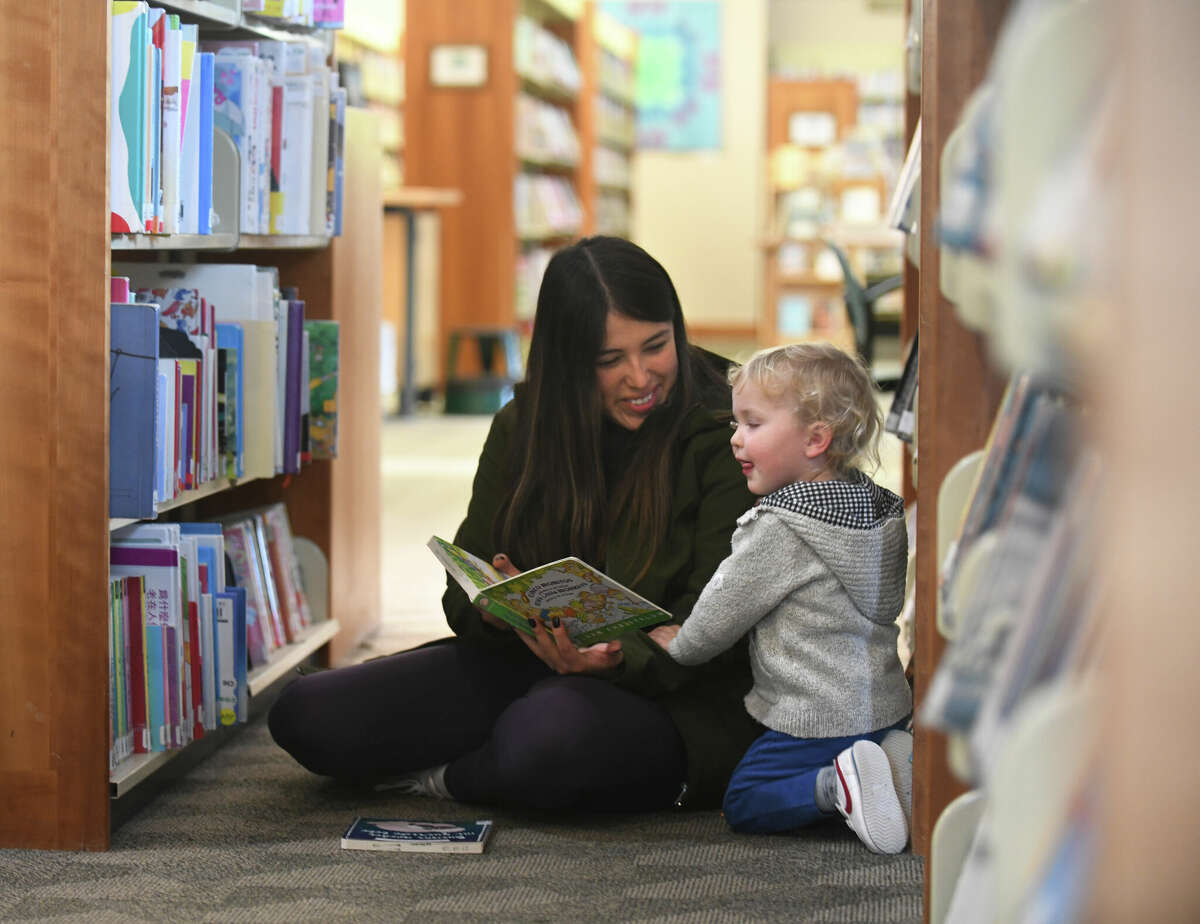 Cos Cob's Paola Dorado and Teddy Baker, 2, read a book in the aisles of Cos Cob Library in the Cos Cob section of Greenwich, Conn. Monday, Oct. 24, 2022. Cos Cob Library is at the very beginning of a refurbishment and renovation project.