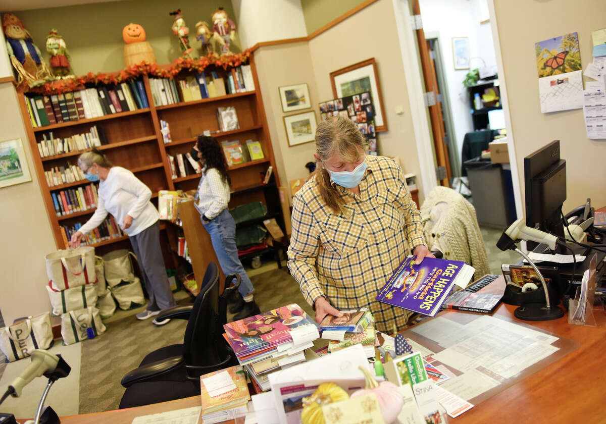 Librarian Kathi Mullins sets aside reserved copies of books at Cos Cob Library in the Cos Cob section of Greenwich, Conn. Monday, Oct. 24, 2022. Cos Cob Library is at the very beginning of a refurbishment and renovation project.