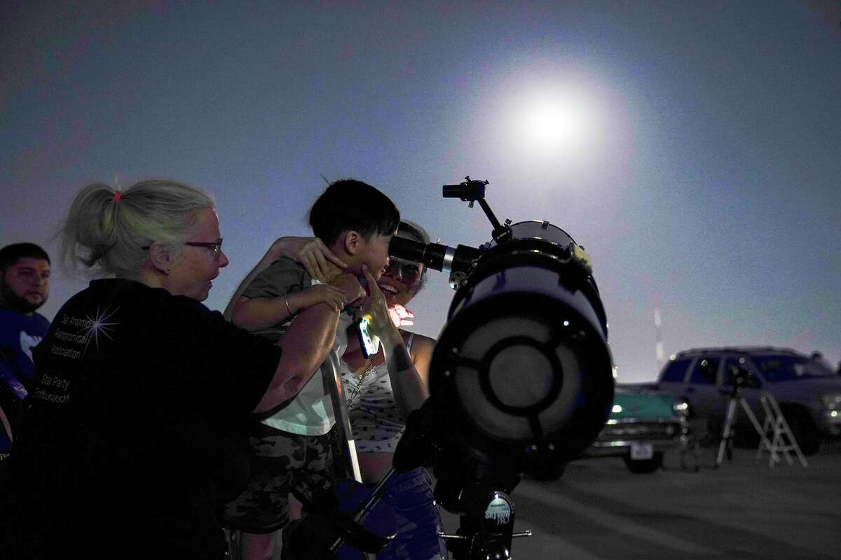 Jennie Haywood helps Aiden Gandara, 3, and his mother, Yen Ganbara view a lunar eclipse outside the Scobee Education Center at San Antonio College last May.