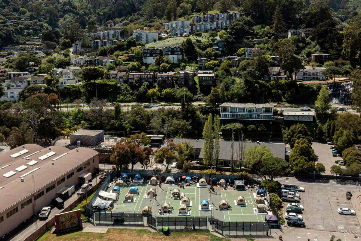 A sanctioned encampment on the Marinship Tennis Court in Sausalito, Calif., Wednesday, April 6, 2022, with a few of homes on the hills above.