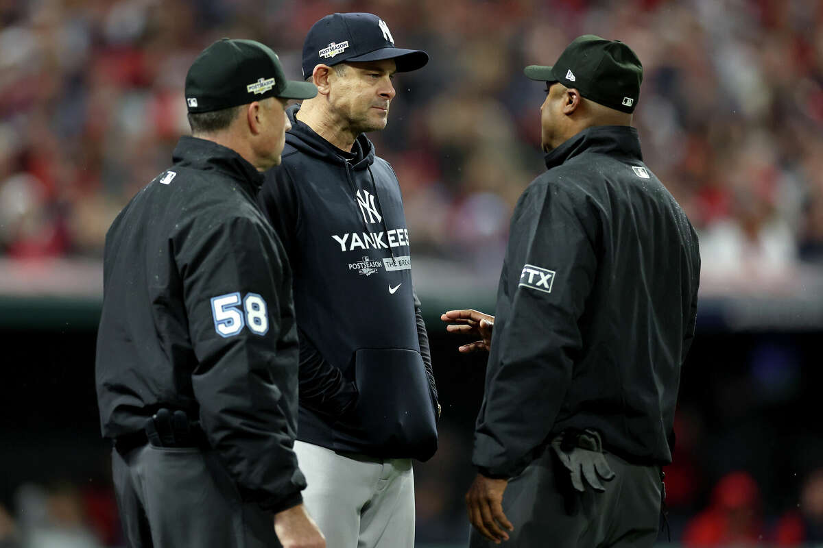 CLEVELAND, OHIO - OCTOBER 16: Aaron Boone #17 of the New York Yankees speaks with umpire's Dan Iassogna #58 and Alan Porter #64 during the second inning against the Cleveland Guardians in game four of the American League Division Series at Progressive Field on October 16, 2022 in Cleveland, Ohio. (Photo by Christian Petersen/Getty Images)