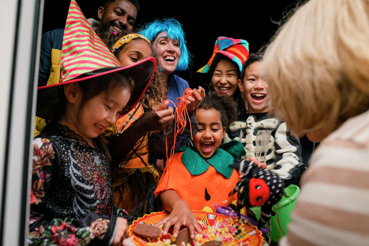 Trick or treaters dig into a bowl of candy on Halloween.