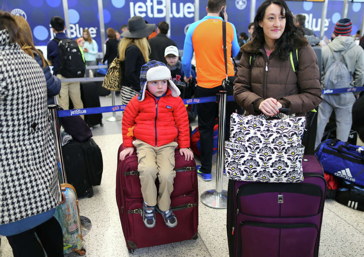 Sam Butland, 4, from Rye, N.H., waits in the line at Jet Blue with his mother, Danielle, right, as they are going to Punta Cana, Dominican Republic. 