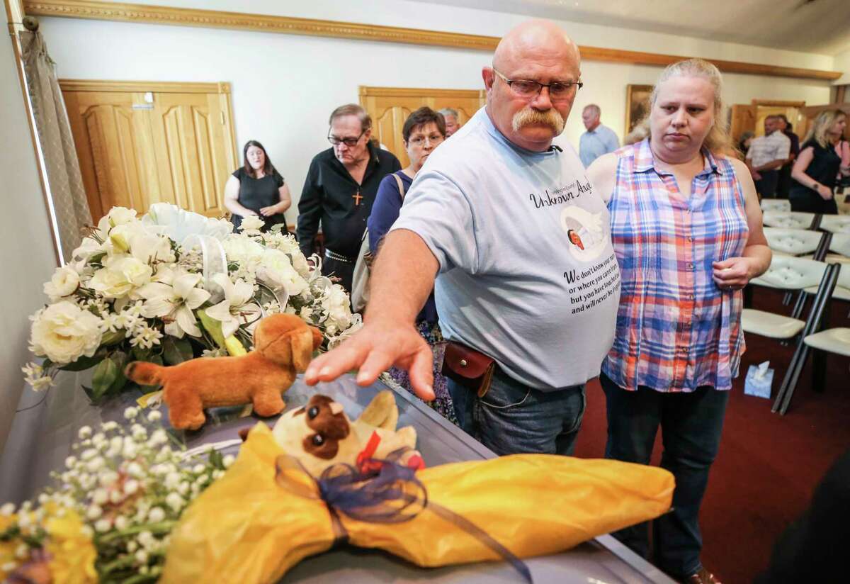Jeffrey Meredith reaches out to touch the stuffed animal atop the casket for an unidentified young boy during a memorial service at Weathers Funeral in June in Salem, Ind. A boy found dead inside a suitcase last spring in rural southern Indiana has been identified as a 5-year-old from Georgia, and police said Oct. 26, that the child’s mother and another woman are suspects in his death. Courier Journal via AP, File)