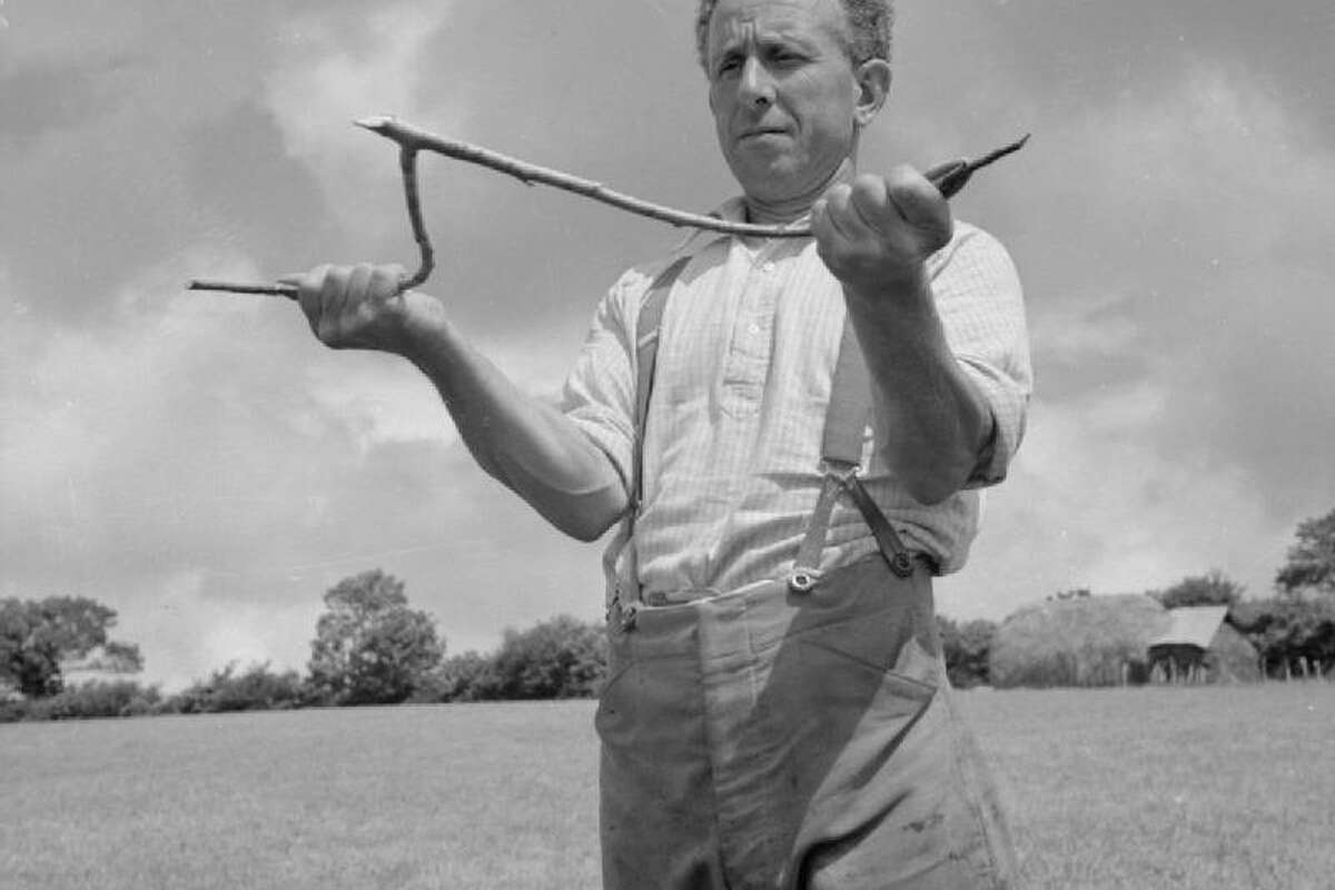 George Casely uses a hazel twig to find water on the land around his farm in Devon, England in 1942.