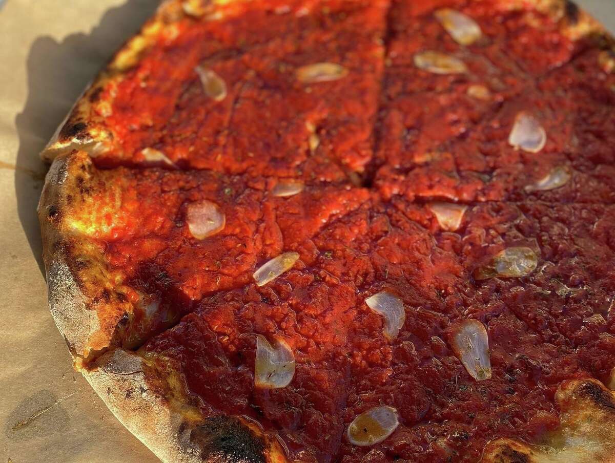 A tomato pie at Atticus Market in New Haven, featuring a thick layer of sauce and slivered garlic.