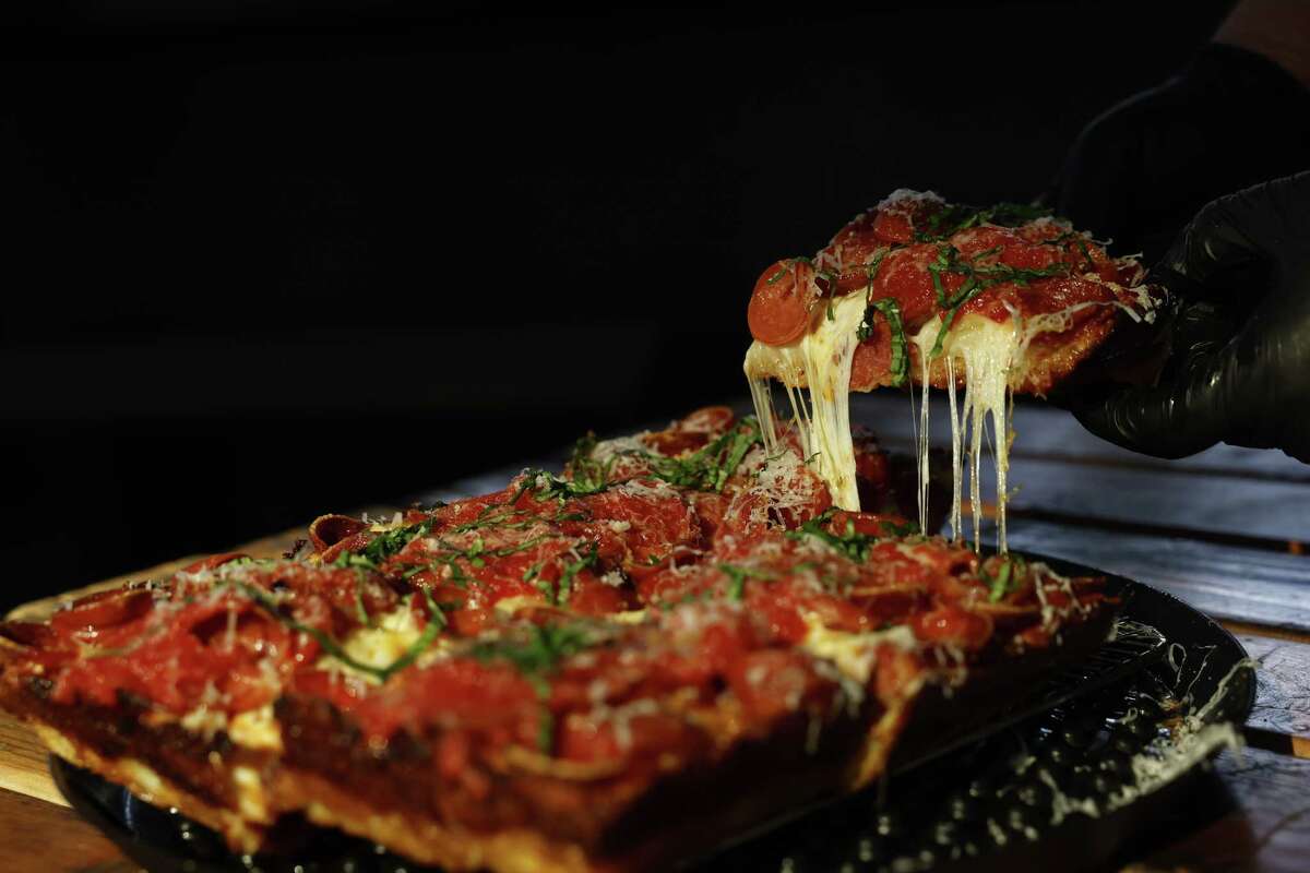 红色的头覆盖着意大利辣香肠和融合了四种奶酪片披萨在圣何塞致敬。