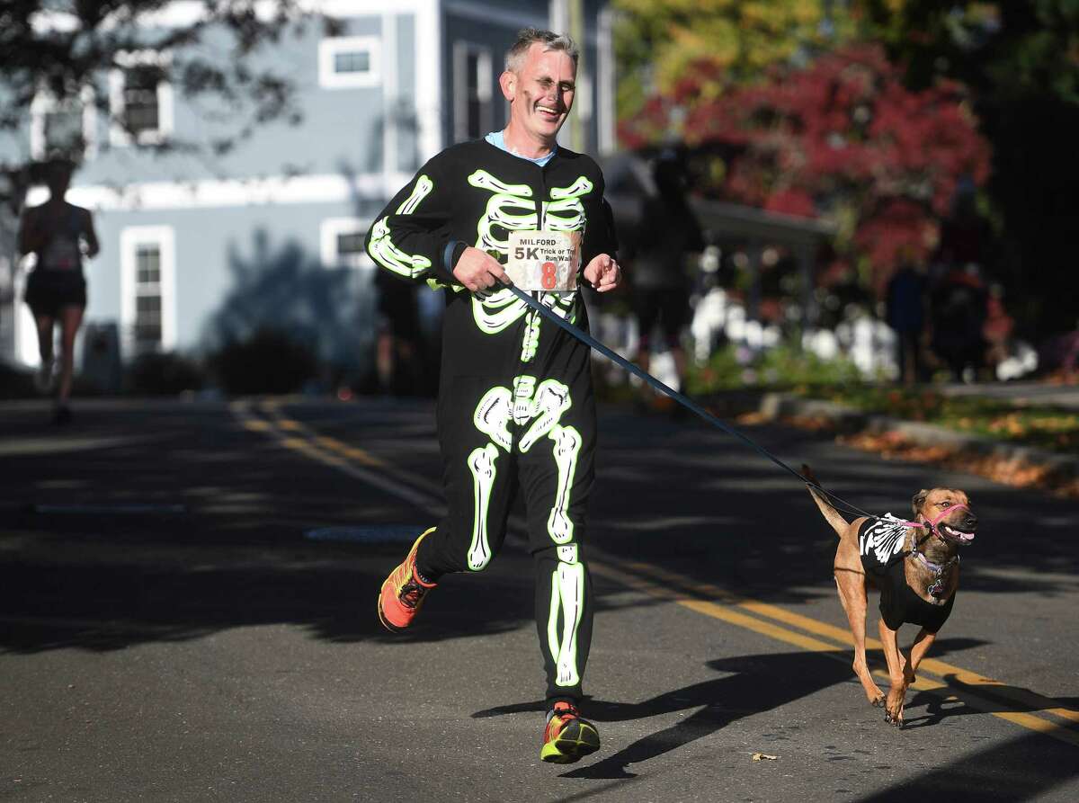 Reverend Matt Lindeman of St. Peter's Episcopal Church in Milford and his dog Izzie race to the finish in their Halloween costumes at the annual Trick or Trot 5k run in Milford, Conn. on Saturday, October 29, 2022.