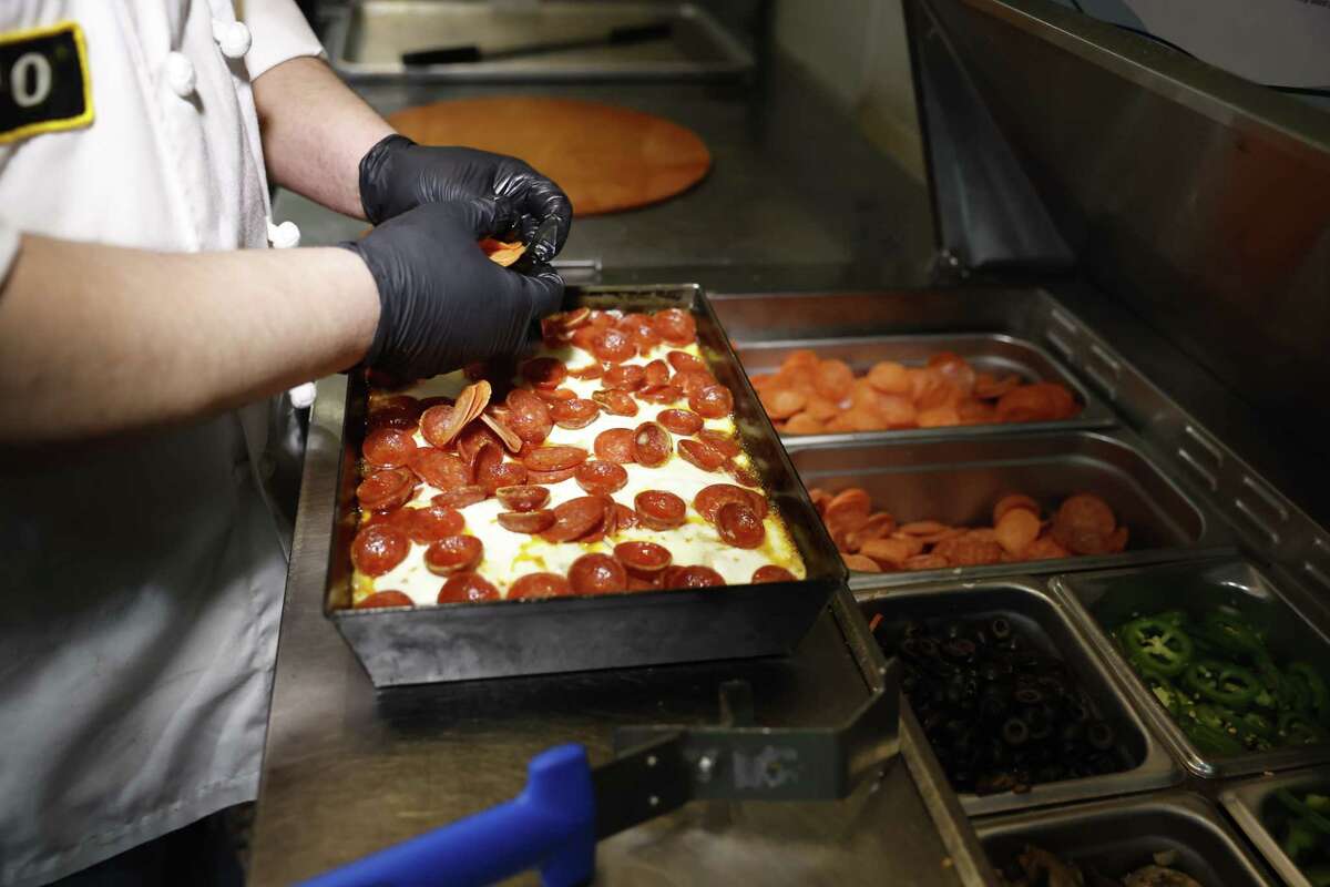 Detroit-style披萨在矩形钢锅煮熟,给边缘特征松脆。