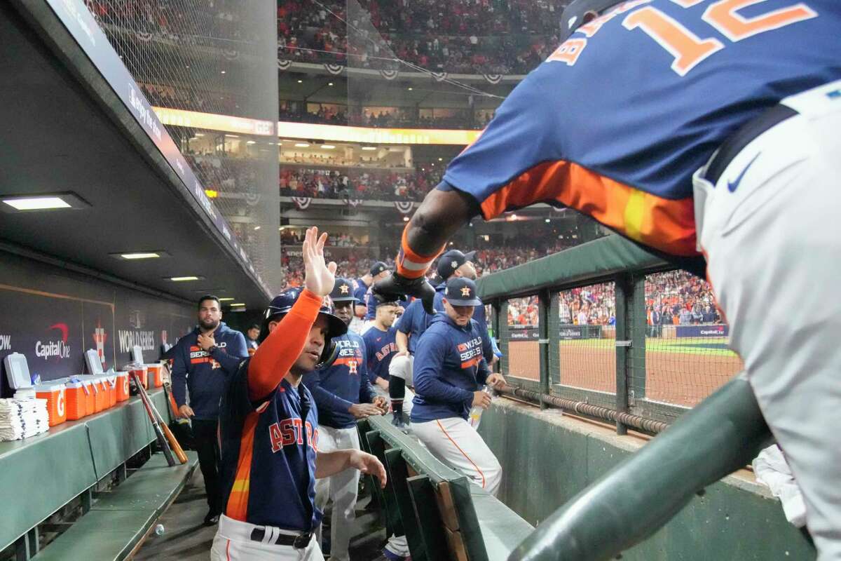 Houston Astros Jose Altuve (27) gets a high-five from Houston Astros manager Dusty Baker Jr. after scoring on Jeremy Peña’s RBI double in the first inning during Game 2 of the World Series at Minute Maid Park on Saturday, Oct. 29, 2022, in Houston.
