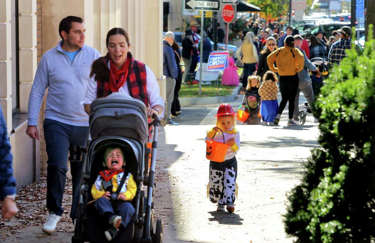 James DeLuca, 1, gets a bit cranky in his stroller as his mother, Laura, his father, Tom, and sister, Stella, 3, take part in the 2022 Greet and Treat Halloween celebration along Greenwich Avenue in Greenwich, Conn., on Saturday October 29, 2022. The event was sponsored by Greenwich Moms and Greenwich Magazine, and offered two Kid Zones: a touch-a-truck police car/fire truck area and a DJ with a bubble show. There was also a family Halloween costume photo contest and trick-or-treating at businesses. Stamford Health is the presenting sponsor. Kathleen Silard, Stamford Health President and CEO, added, "As a Greenwich resident, it is truly heartwarming to see how "Greenwich Moms" is providing our children with a fun way to celebrate Halloween safely and that we are able to hold these types of public events once again."