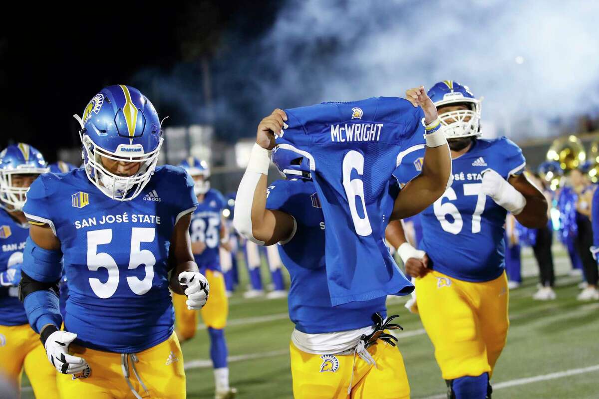 The San Jose State Spartans football team honors their teammate Camdan McWright (6) as running back Kairee Robinson (32) runs onto the field holding McWright's jersey before their game against the Nevada Wolf Pack in San Jose, Calif., on Saturday, Oct. 29, 2022.