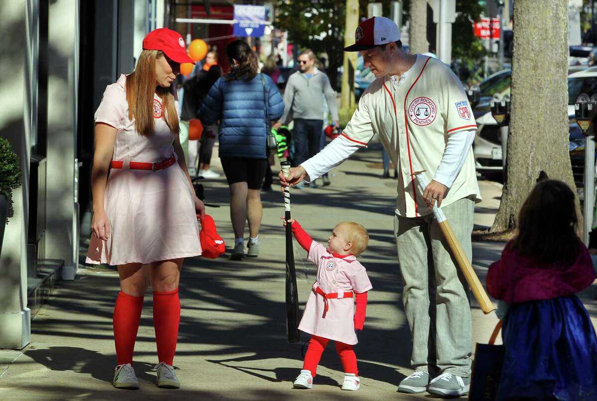 Robert and Rebecca Burns and their child Hunter, 2, dressed up as characters from "A League of Thier Own" as they take part in the 2022 Greet and Treat Halloween celebration along Greenwich Avenue in Greenwich, Conn., on Saturday October 29, 2022. The event was sponsored by Greenwich Moms sand Greenwich Magazine and offered two Kid Zones: a touch-a-truck police car/fire truck area and a DJ with a bubble show. There was also a family Halloween costume photo contest and trick-or-treating at businesses. Stamford Health is the presenting sponsor. Kathleen Silard, Stamford Health President and CEO, added, "As a Greenwich resident, it is truly heartwarming to see how "Greenwich Moms" is providing our children with a fun way to celebrate Halloween safely and that we are able to hold these types of public events once again."