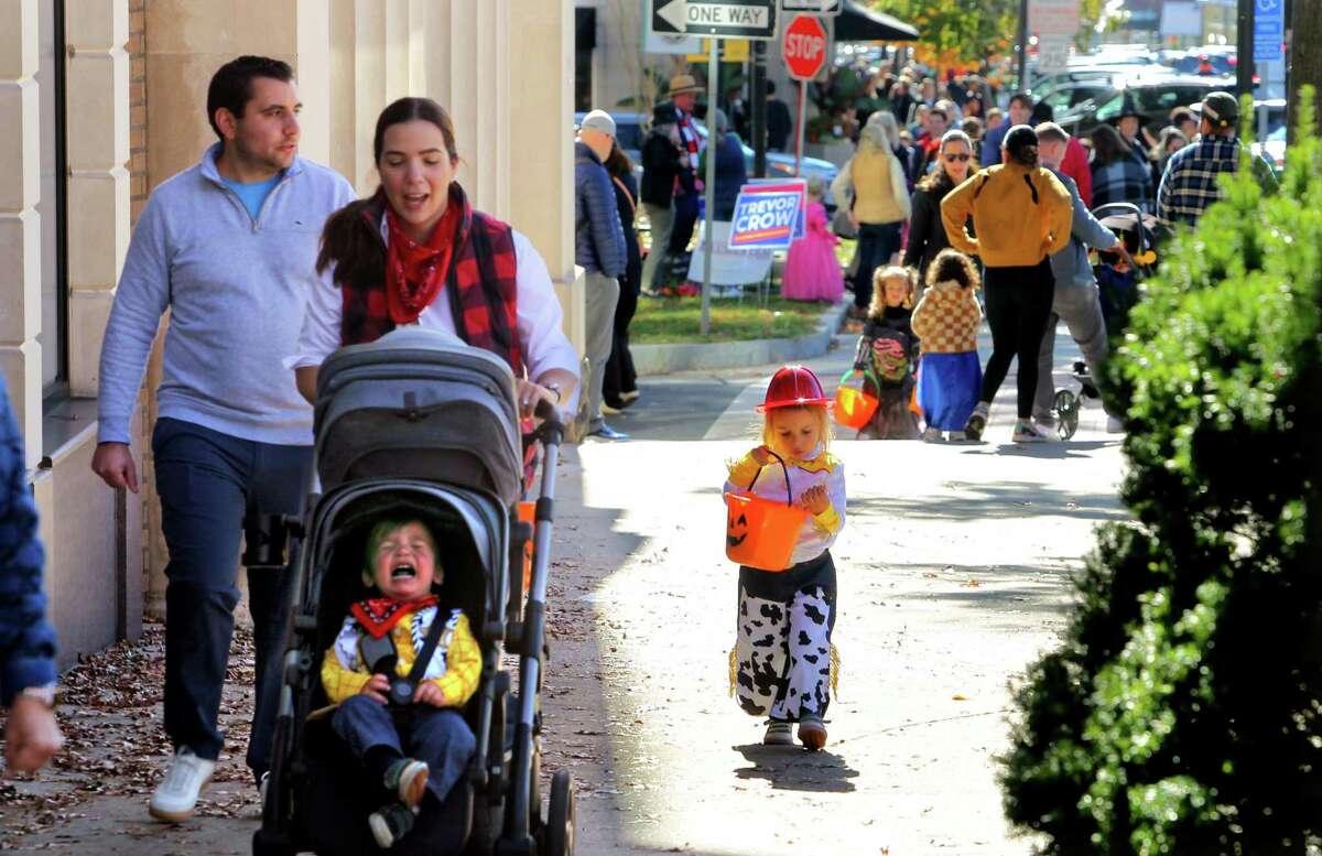 James DeLuca, 1, gets a bit cranky in his stroller as mom Laura, dad Tom and sister Stella, 3, take part in the 2022 Greet and Treat Halloween celebration along Greenwich Avenue in Greenwich, Conn., on Saturday October 29, 2022. The event was sponsored by Greenwich Moms sand Greenwich Magazine and offered two Kid Zones: a touch-a-truck police car/fire truck area and a DJ with a bubble show. There was also a family Halloween costume photo contest and trick-or-treating at businesses. Stamford Health is the presenting sponsor. Kathleen Silard, Stamford Health President and CEO, added, "As a Greenwich resident, it is truly heartwarming to see how "Greenwich Moms" is providing our children with a fun way to celebrate Halloween safely and that we are able to hold these types of public events once again."