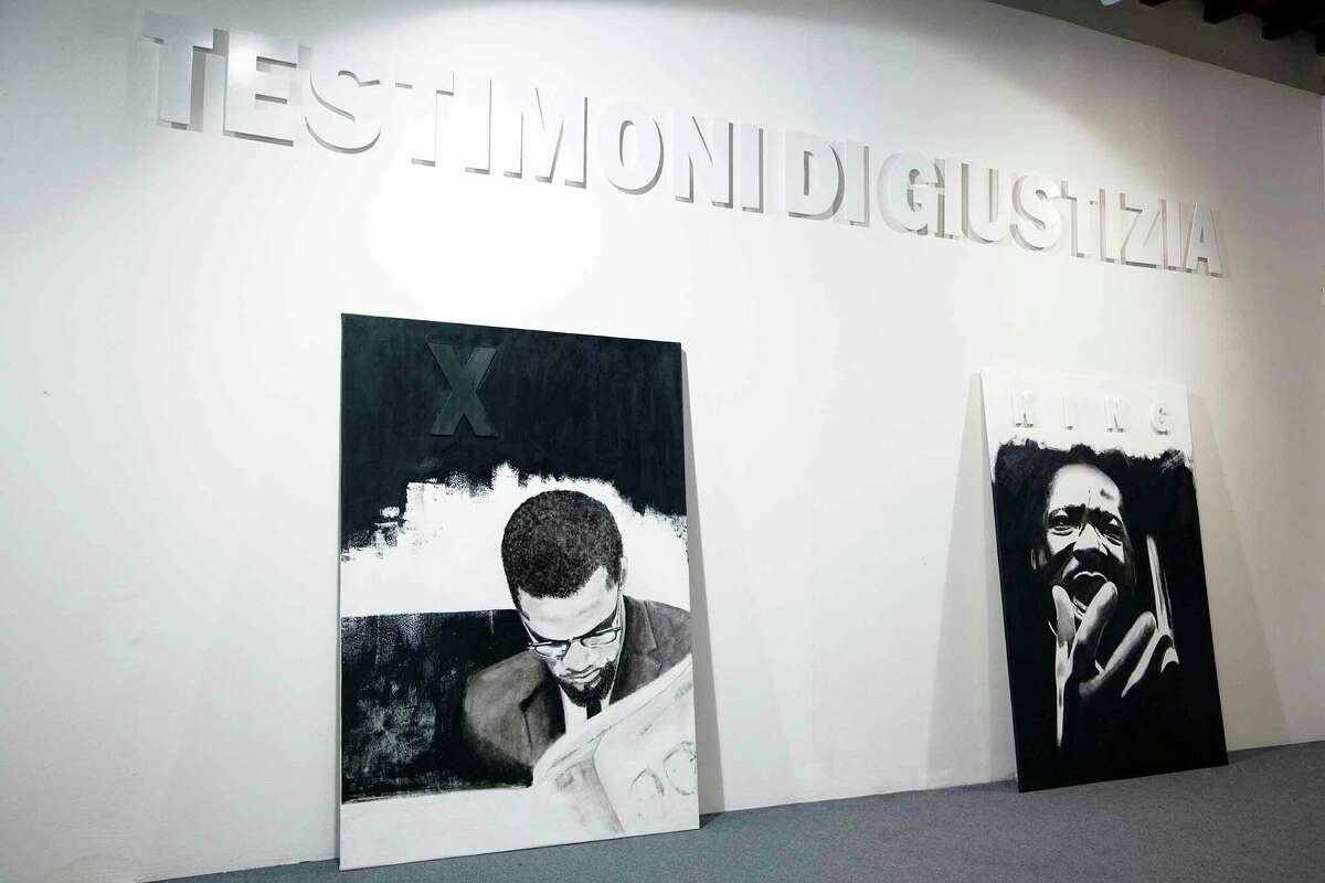 Jerry Lee Ingram's portraits of Malcom X (left) and Martin Luther King Jr. rest under an Italian sign that translates to "Witnesses of Justice," the title of Ingram's social justice exhibit as part of the European Festival of Philosophy in Modena, Italy.