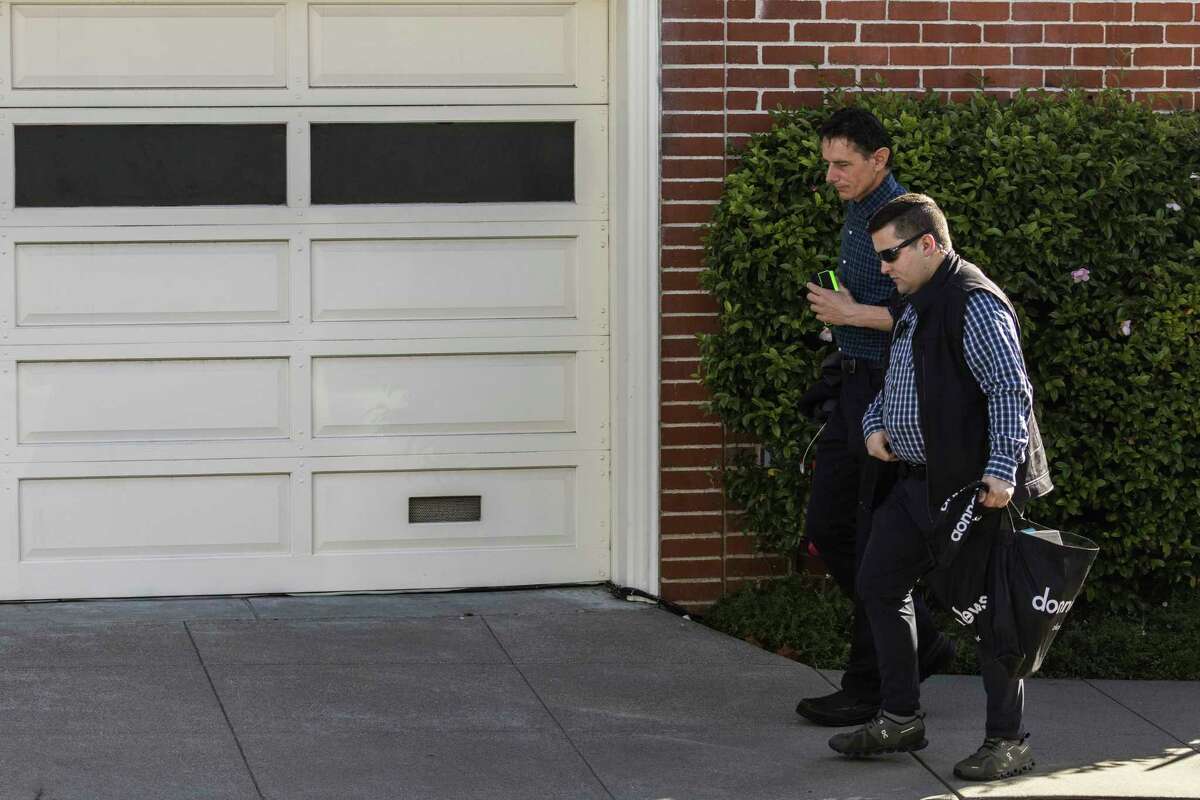 Paul Pelosi Jr., lad   of U.S. Speaker of the House Nancy Pelosi and Paul Pelosi, background, walks with a information    unit   extracurricular  his parents' location  connected  Saturday, Oct. 29, the time  aft  an intruder violently attacked Paul Pelosi astatine  the location  successful  San Francisco.