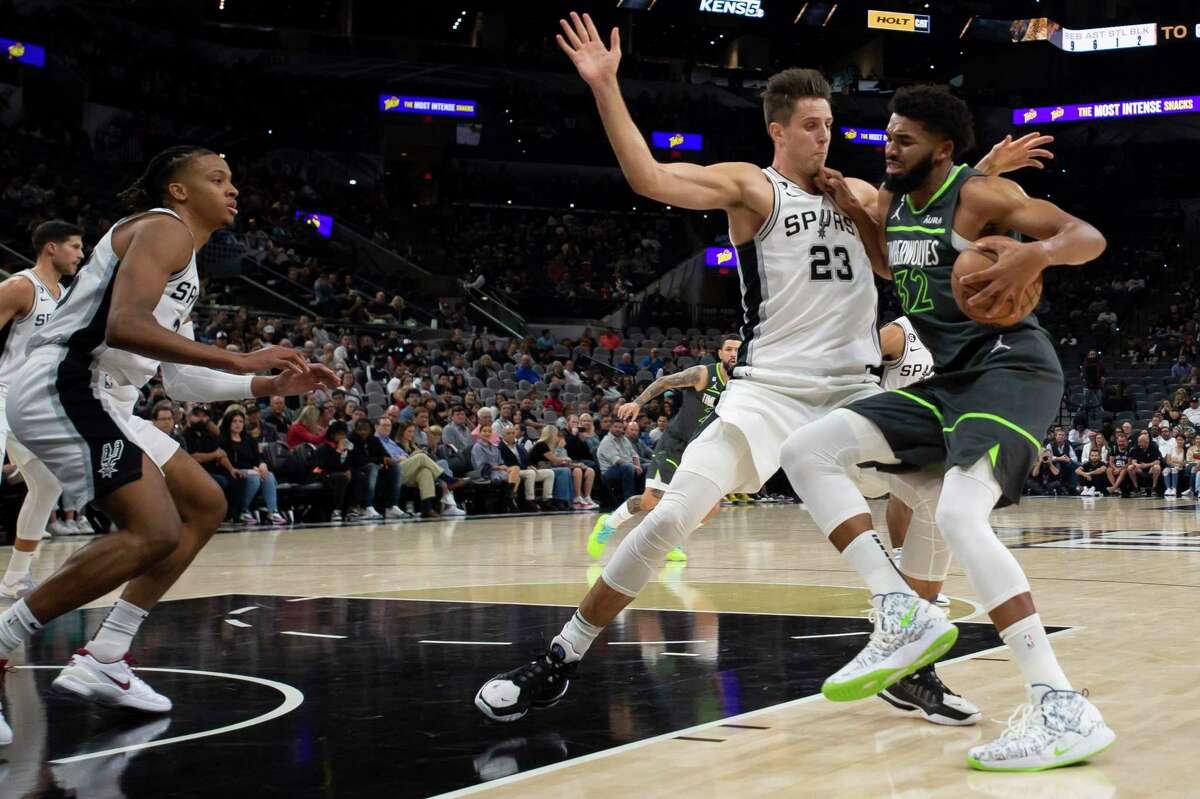 Minnesota Timberwolves' Karl-Anthony Towns (32) drives against San Antonio Spurs' Zach Collins (23) and Romeo Langford during the first half of an NBA basketball game, Sunday, Oct. 30, 2022, in San Antonio. (AP Photo/Darren Abate)