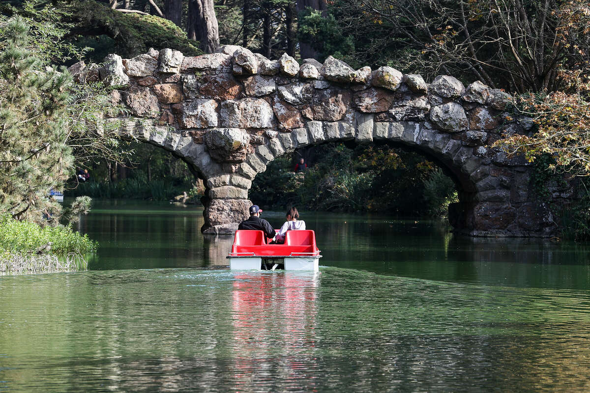 People ride a pedal boat on Stow Lake during autumn in Golden Gate Park in San Francisco, California, on October 20, 2022.