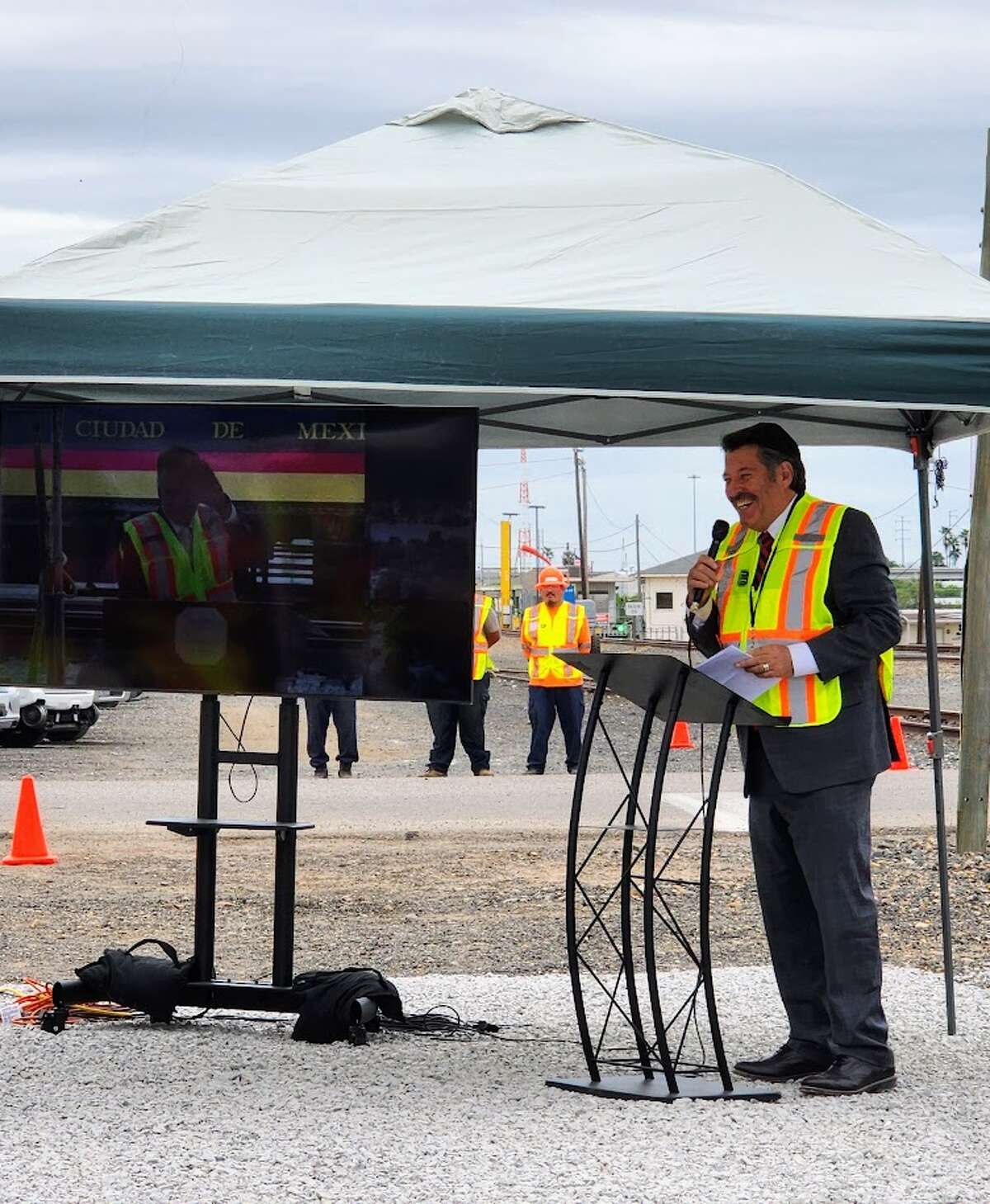 Laredo Mayor Pete Saenz speaks at Monday's groundbreaking ceremony in Laredo while a screen shows a live feed from the groundbreaking ceremony in Nuevo Laredo.