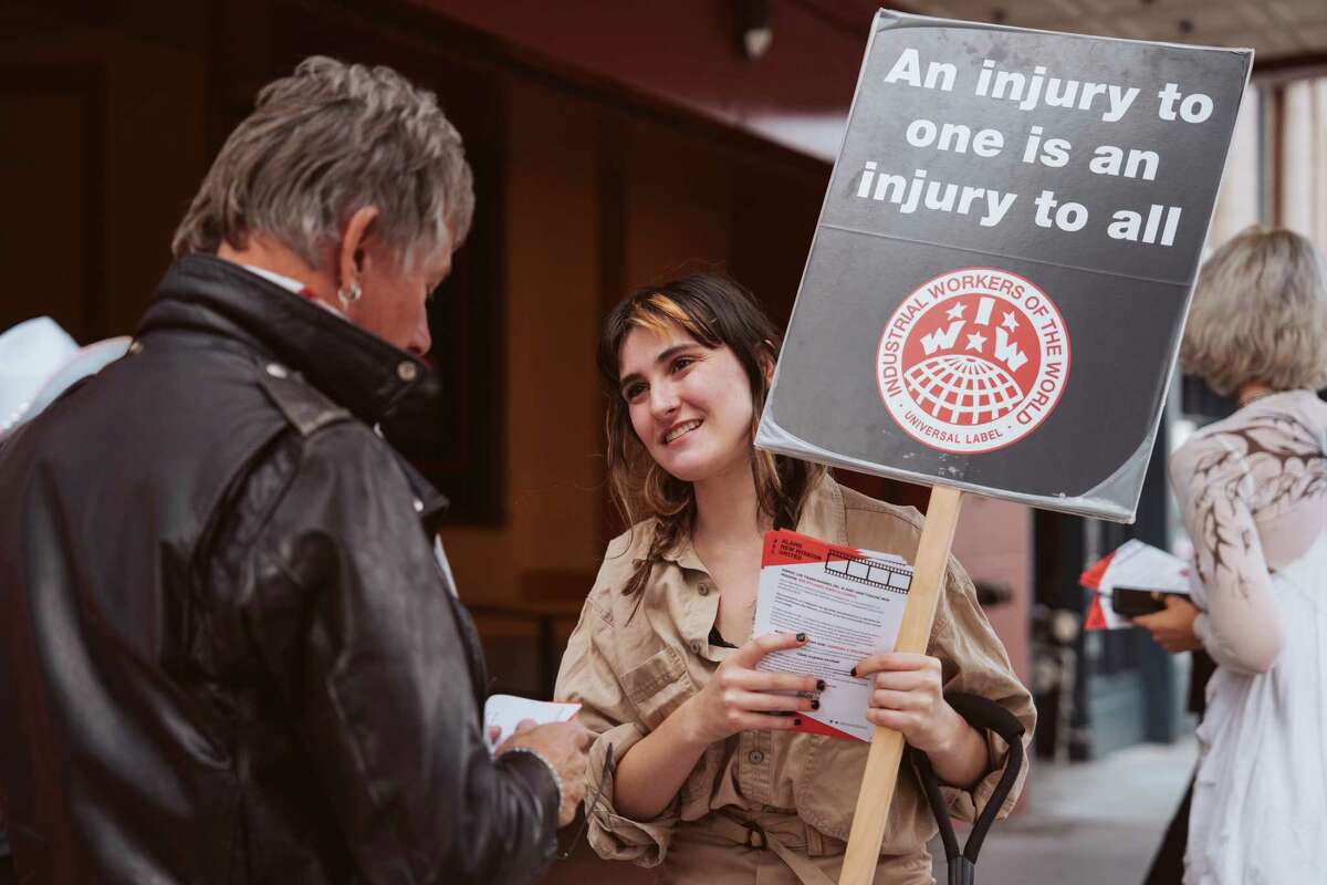 Alamo Drafthouse employee Olly DeStefano talking to a passer-by outside the theater during a demonstration for their union affiliated with the IWW on Oct. 31, 2022 in San Francisco, Calif.