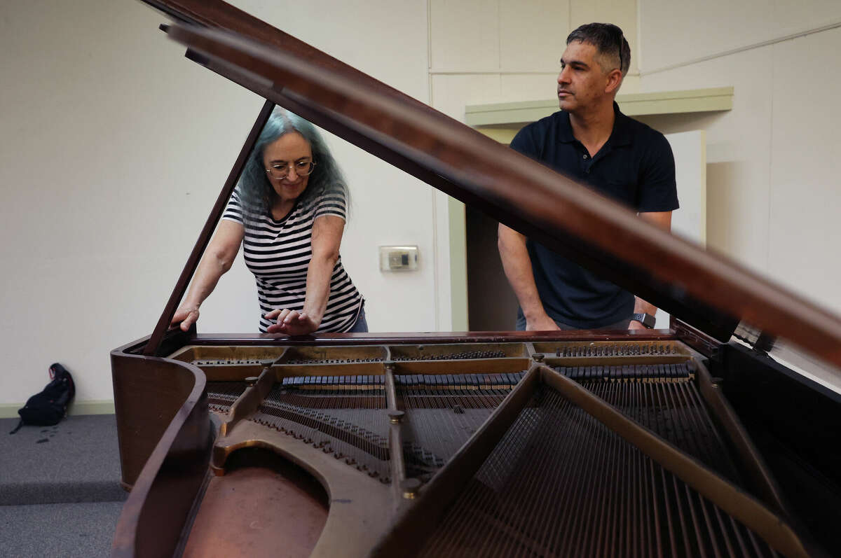 Dana Clark (left) and Michael Pugh inspect a 100-year-old, abandoned baby grand piano that was at risk of being destroyed when the building it's in is demolished in the coming weeks. 
