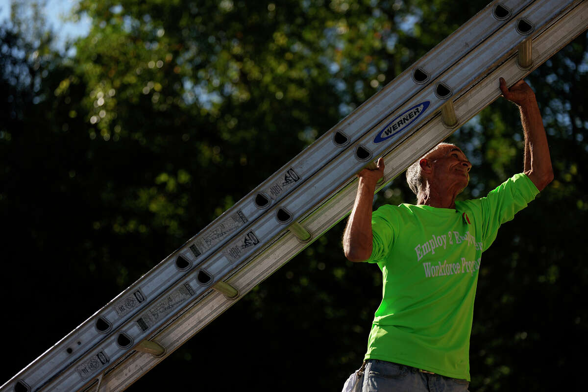 Doug Cope, 62, picks up a ladder to climb it as he prepares to put a fresh coat of paint on a facility at the Jim and JoAnn Fonteno Family Park, Wednesday, Oct. 26, 2022, in Houston. Cope was presented with the opportunity to works through the Harris County's Employ2Empower program, which is designed to provide support to individuals experiencing homelessness.