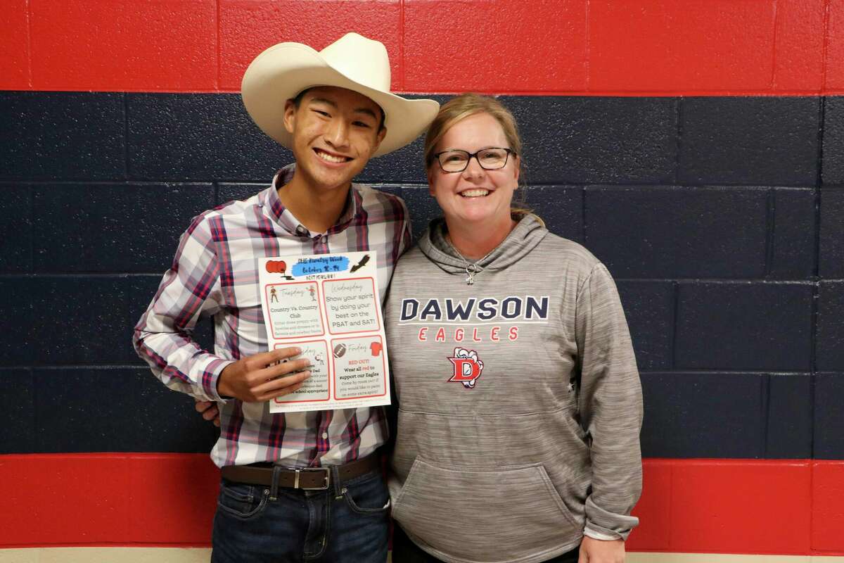 Dawson High School student council president Tanner Tran, shown with council co-sponsor Teri Zuteck, holds a schedule for Dawson's "Rivalry Week" activities in October leading up to the big game against Pearland. The cowboy attire reflects his participation in the "Country vs. Country Club" theme for one of the days.