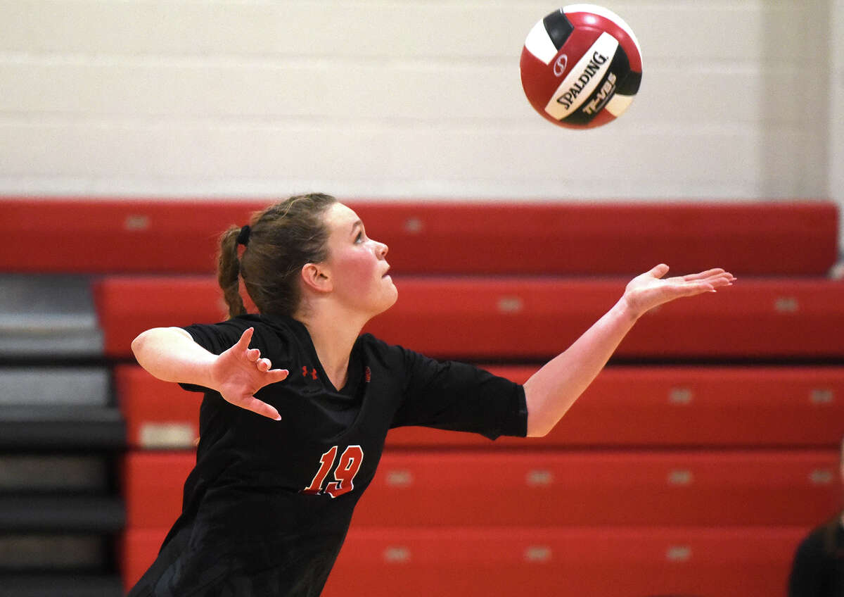 New Canaan's Lily Stevens (19) serves during a volleyball match against Wilton in New Canaan on Thursday, Sept. 29, 2022.