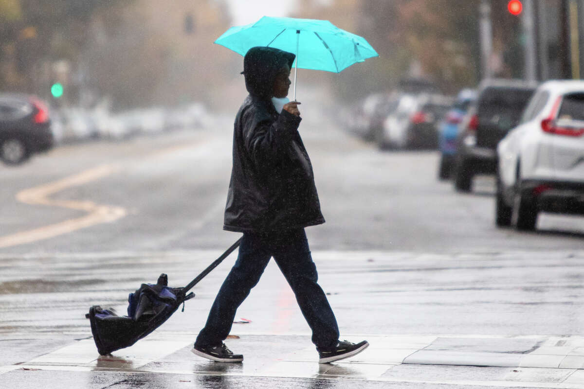 A woman crosses a street during a rain storm in Alameda, Calif. on Nov 1, 2022.