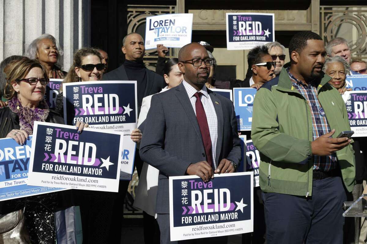 Oakland mayoral candidate Loren Taylor holds a sign for fellow candidate Treva Reid as they announce they will form an alliance for ranked choice voting in a press conference at Oakland City Hall on Wednesday, Oct. 26, 2022.