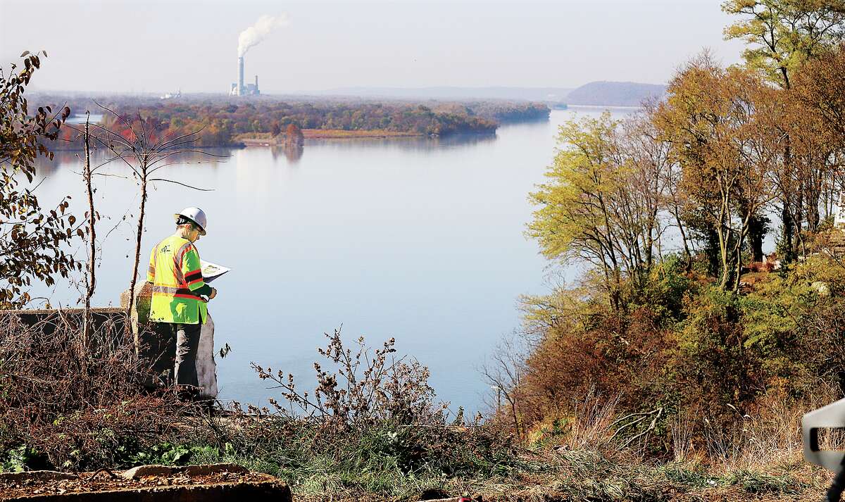 John Badman|The Telegraph A worker from GeoStabalization International, based in Commerce City, Colorado, looks over maps at the edge of the collapsed bluff Tuesday on Rivervieww Drive in Alton as work begins on the project. 