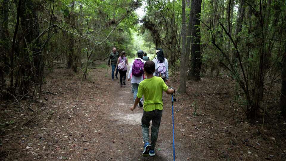 Families walk through the wetland loop during a one-mile guided hike around the Spring Creek Greenway Nature Center, Thursday, July 9, 2021, in Spring. The nature center will offer a variety of interactive services throughout the rest of July as they were unable to due to do COVID-19 pandemic the past year.