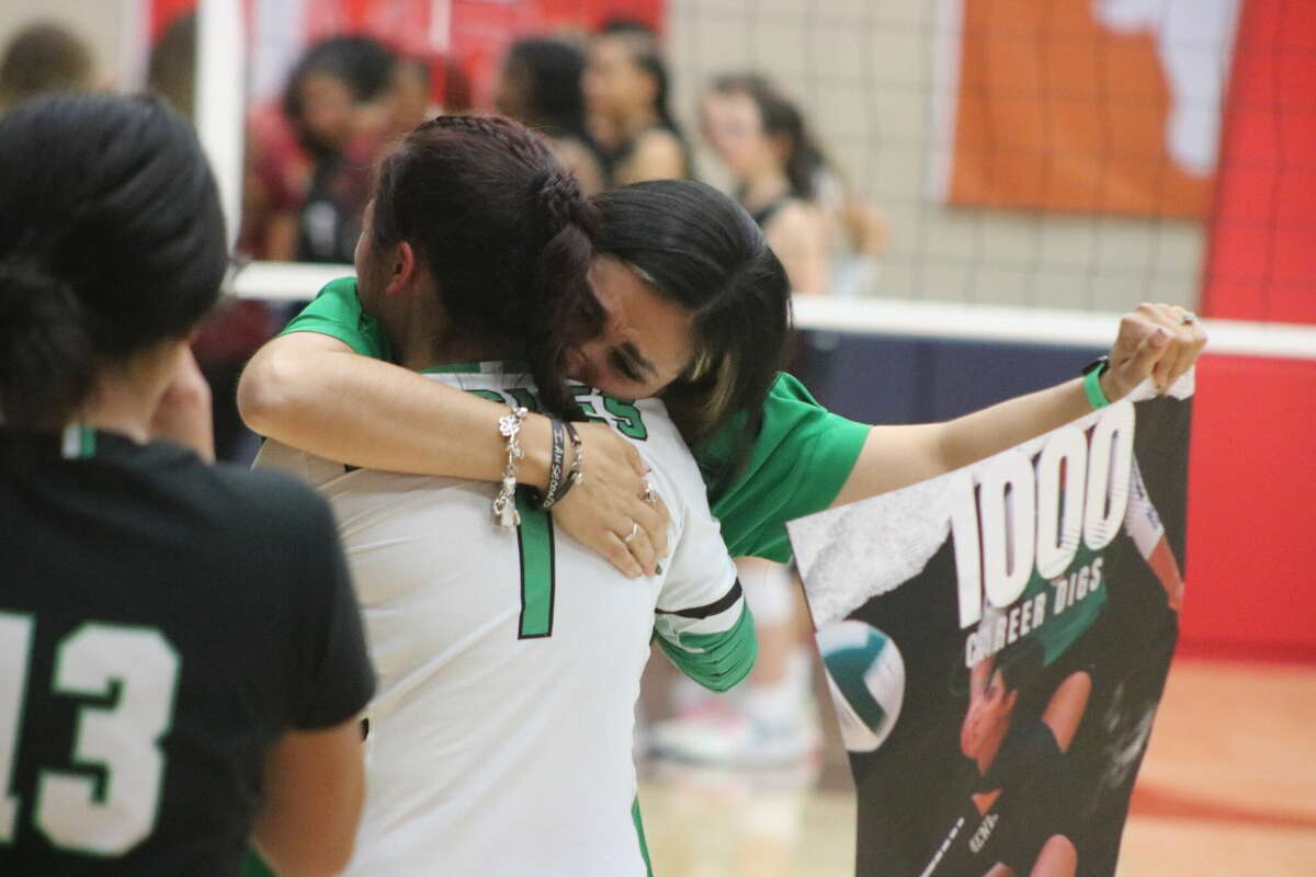 Pasadena head coach Carmen Martinez tearfully hugs libero Angelina Cruz while holding a poster of Cruz's accomplishment of 1000 digs in her high school career that ended Tuesday night.