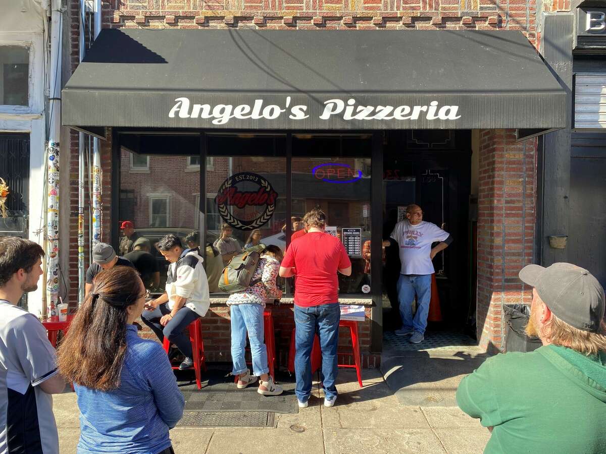Customers wait for their food outside Angelo's Pizzeria in Philadelphia while the man they call Vinnie Boombatz watches the door on Wednesday. The owner of Angelo's was featured in a viral video when he said he turned down a request to make pizzas for the Astros at the World Series.