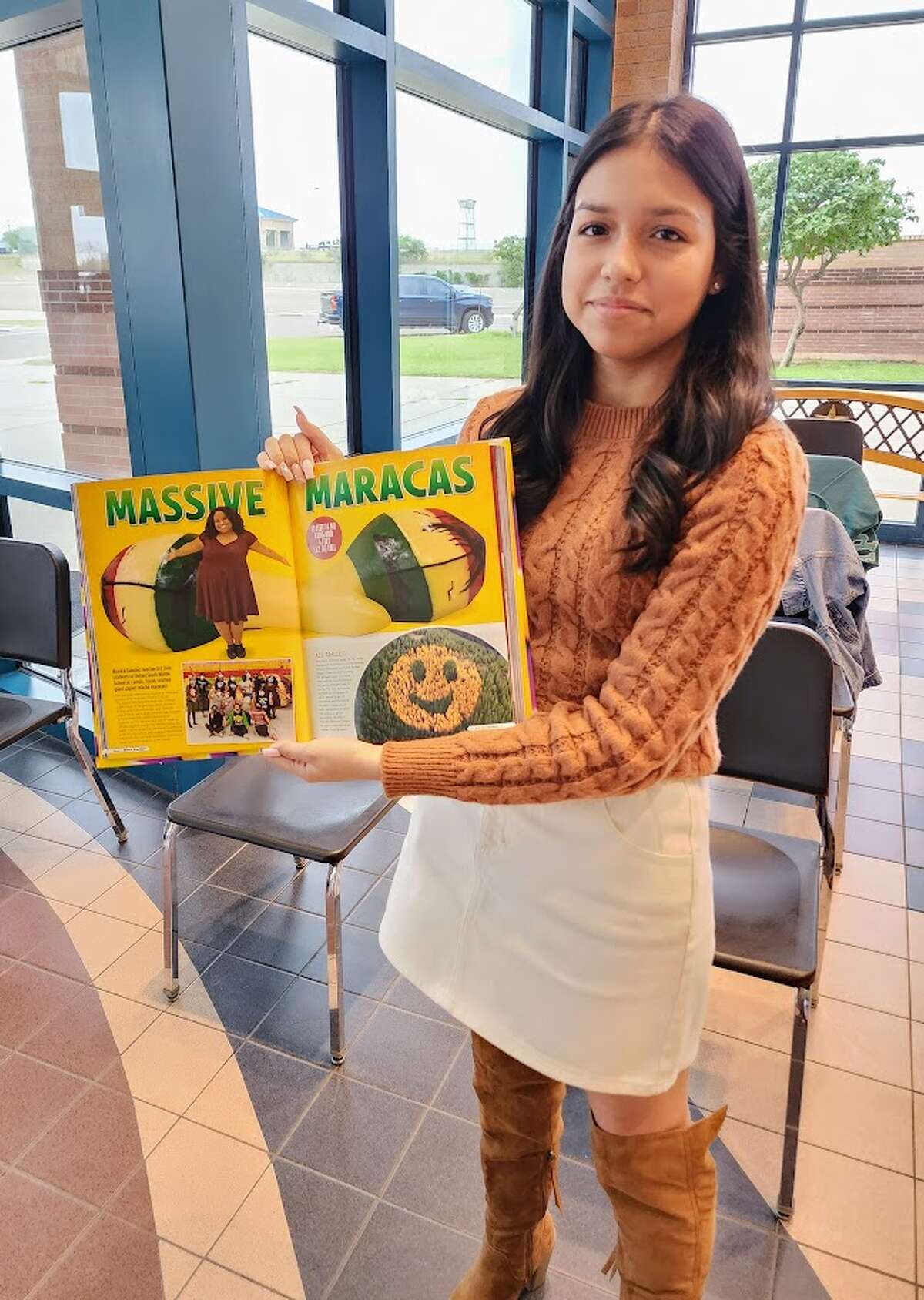 United South High School sophomore Iris Rosas holds up a copy of the latest Ripley's Believe It or Not! book which features the art project of giant papier-mache maracas created by United South Middle School teacher Monika Sanchez and her former students.