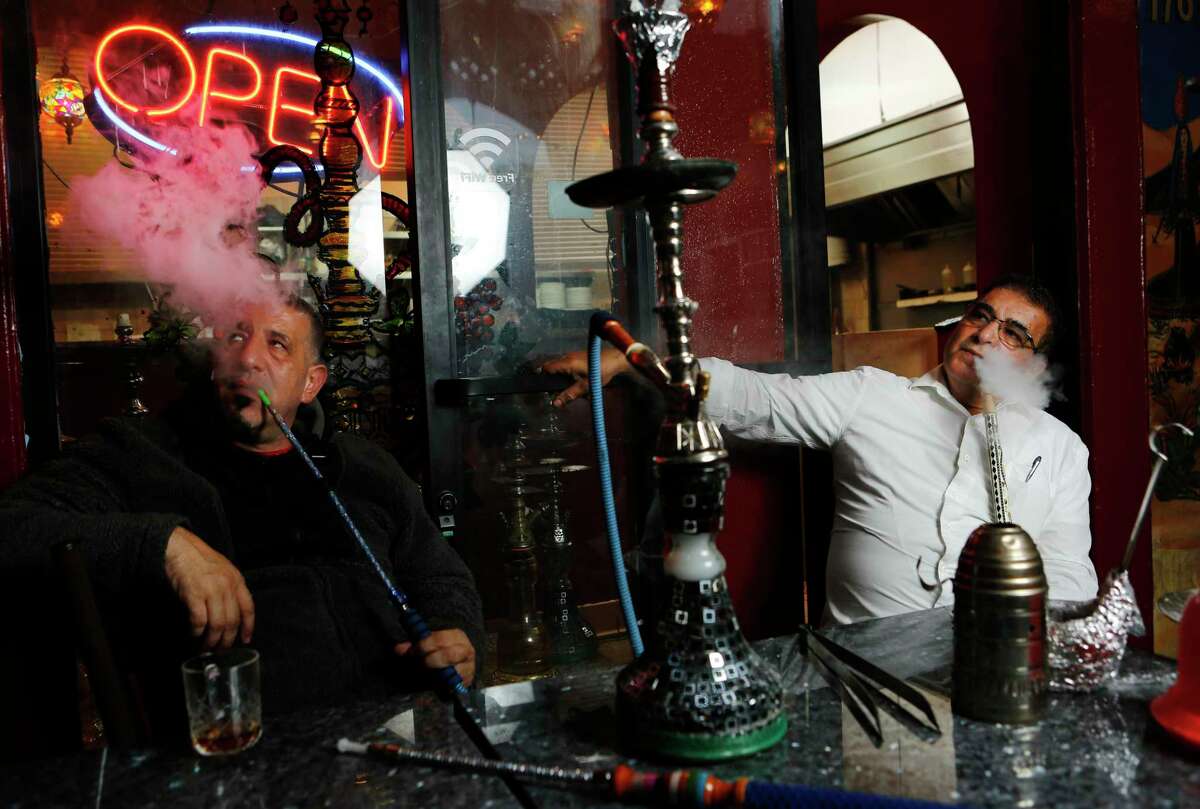 Khaled Shehadeh and owner Adnan Abu Sharkh smoke a hookah at Pride of the Mediterranean restaurant in San Francisco in 2018. Hookahs would be exempted from Prop. 31’s ban on flavored tobacco.