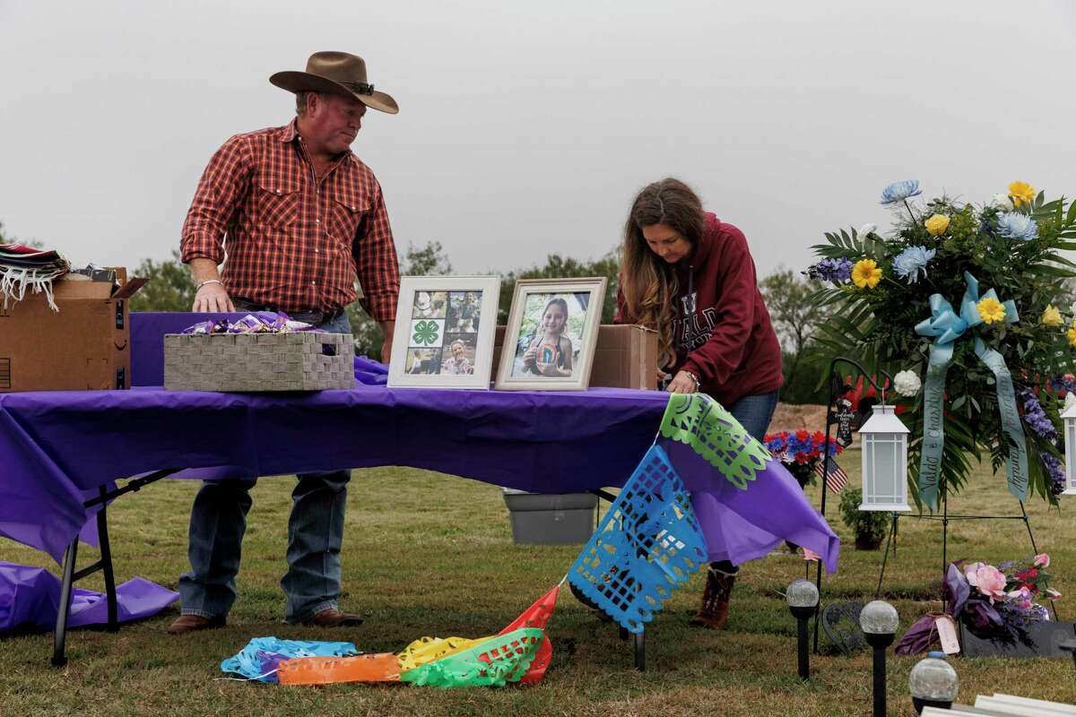 Chris Seiler and April Elrod, parents of slain fourth-grader Makenna Elrod, build an altar at her gravesite at Hillcrest Memorial Cemetery in Uvalde on Wednesday. To mark Día de los Muertos, the families of the Robb Elementary School shooting victims gathered at the cemetery after sundown to celebrate their loved ones.
