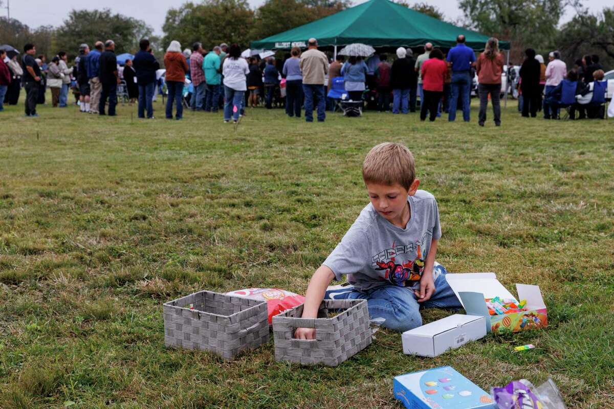Holden Elrod, 8, organizes a basket of keychains and Dum Dum lollipops to set out at his sister Makenna’s gravesite at Hillcrest Memorial Cemetery in Uvalde on Wednesday. To mark Día de los Muertos, the families of the Robb Elementary School shooting victims gathered at the cemetery after sundown to celebrate their loved ones.