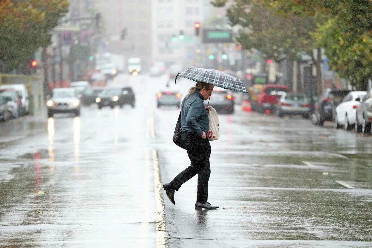 2022年11月1日星期二，加利福尼亚州旧金山，一名行人在阵雨中穿过第六街。